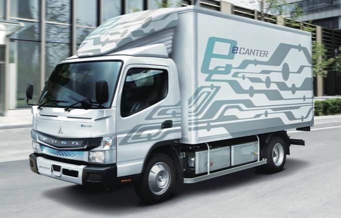 FUSO Canter light-duty truck driving on a road, used for urban delivery and commercial transport.