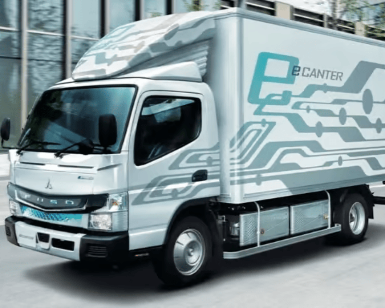 White electric box truck driving through a modern urban area, featuring a circuit-inspired graphic design and eCanter branding on the cargo box.