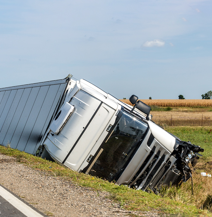 Overturned truck lying in a roadside ditch after an accident in a rural area.