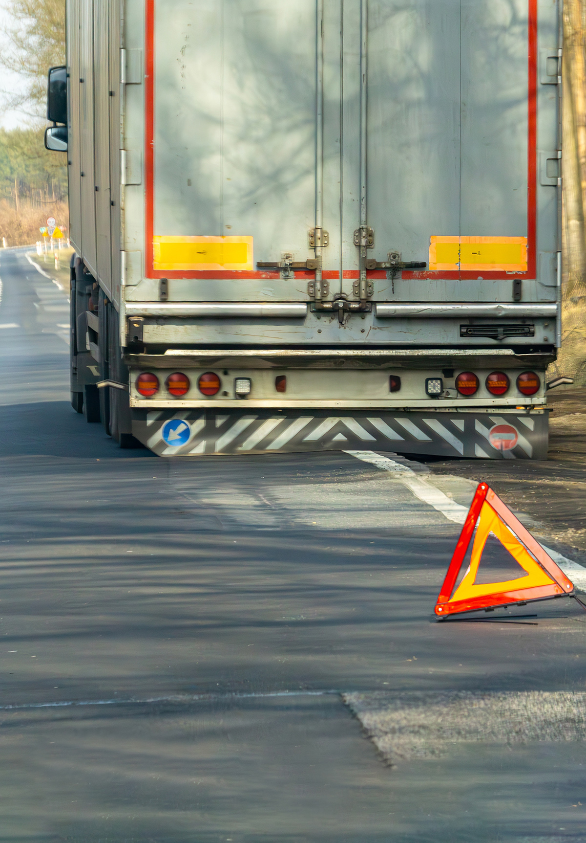 Warning triangle placed on the road behind a stopped truck on a rural roadway.