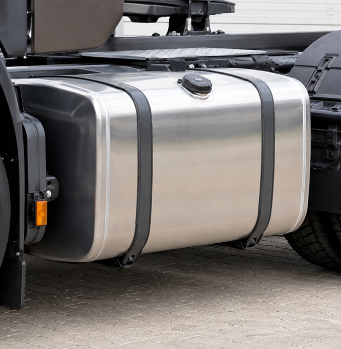 Aluminum Fuel Tank on Heavy-Duty Truck Close-up of a large aluminum fuel tank mounted on the chassis of a heavy-duty truck, secured with two black mounting straps.