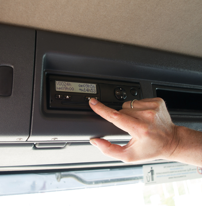 Driver operating a digital tachograph inside a commercial vehicle.