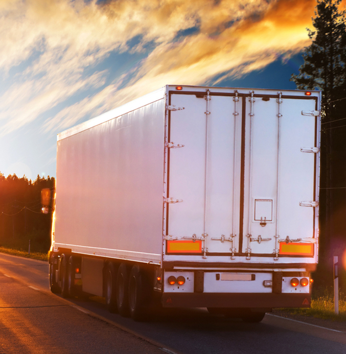 Delivery Truck on the Road at Sunset White delivery truck driving along a rural road at sunset.