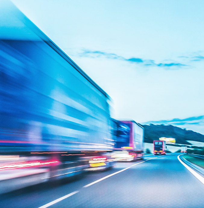 High-Speed Freight Transport on the Highway Motion-blurred semi-trucks driving on a highway at dusk, representing fast and efficient freight transportation.