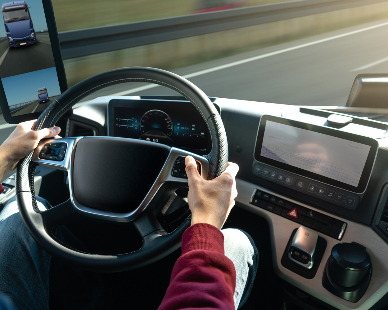 Modern Truck Cabin with Digital Dashboard and Driver Assistance Systems Truck driver operating a modern semi-truck with digital dashboard and advanced driver assistance technology on the highway.