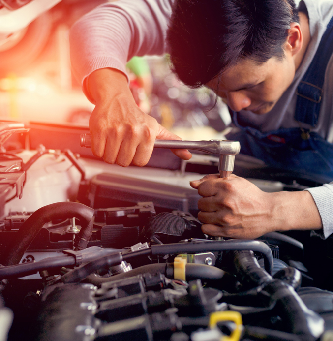 Professional Mechanic Repairing a Car Engine Mechanic using a socket wrench to repair a car engine in an automotive workshop.