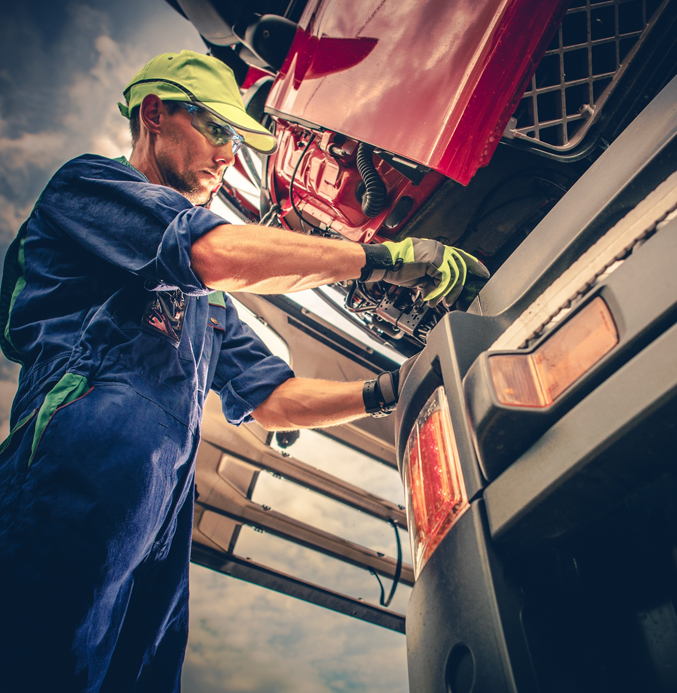 Truck Mechanic Servicing a Commercial Vehicle Engine Truck mechanic performing maintenance on the engine of a commercial truck with the cab tilted forward.
